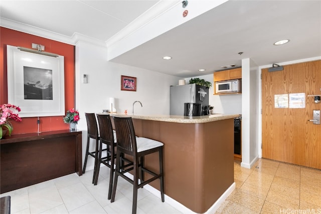 kitchen featuring a breakfast bar area, kitchen peninsula, stainless steel fridge, and crown molding