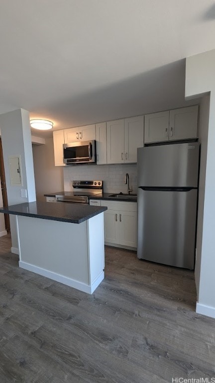 kitchen with stainless steel appliances, hardwood / wood-style floors, sink, white cabinetry, and tasteful backsplash