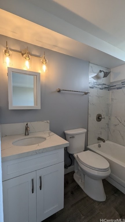 full bathroom featuring vanity, tiled shower / bath combo, hardwood / wood-style flooring, and toilet