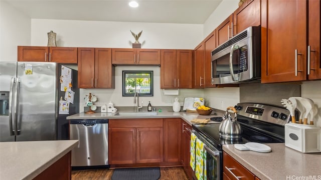 kitchen with appliances with stainless steel finishes, sink, and dark wood-type flooring