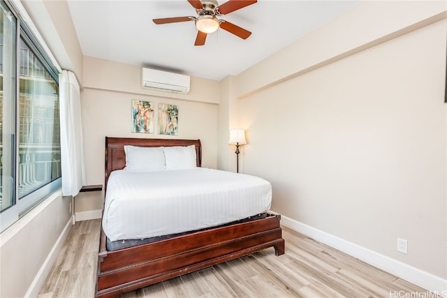 bedroom with a wall mounted air conditioner, light wood-type flooring, and ceiling fan