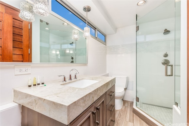 bathroom featuring a shower with door, vanity, hardwood / wood-style floors, and toilet