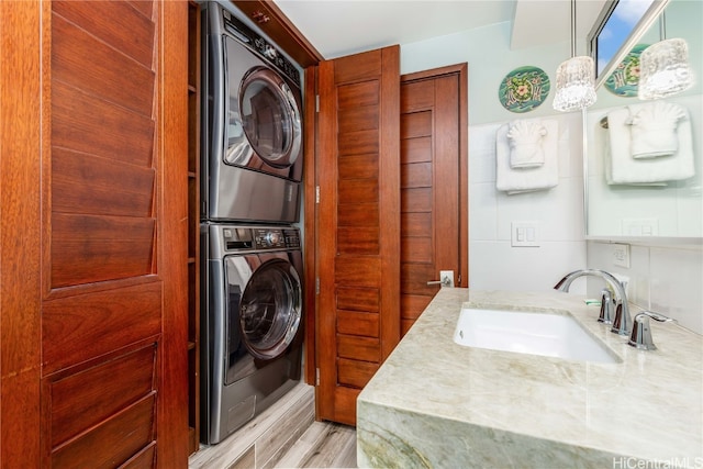 laundry room featuring sink, stacked washer / dryer, and light hardwood / wood-style floors