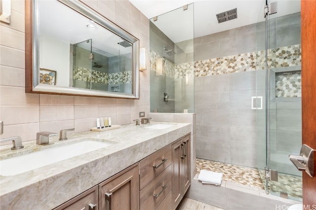 bathroom featuring vanity, decorative backsplash, a shower with shower door, and tile walls