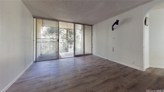 empty room featuring a textured ceiling and dark hardwood / wood-style floors