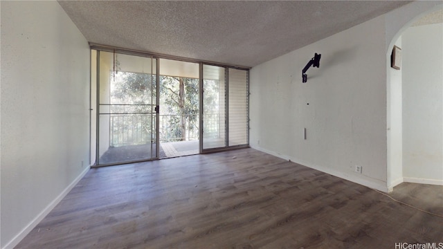 unfurnished room with dark hardwood / wood-style floors, floor to ceiling windows, and a textured ceiling