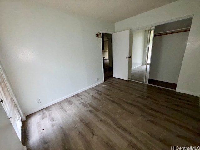 unfurnished bedroom with dark wood-type flooring and a closet