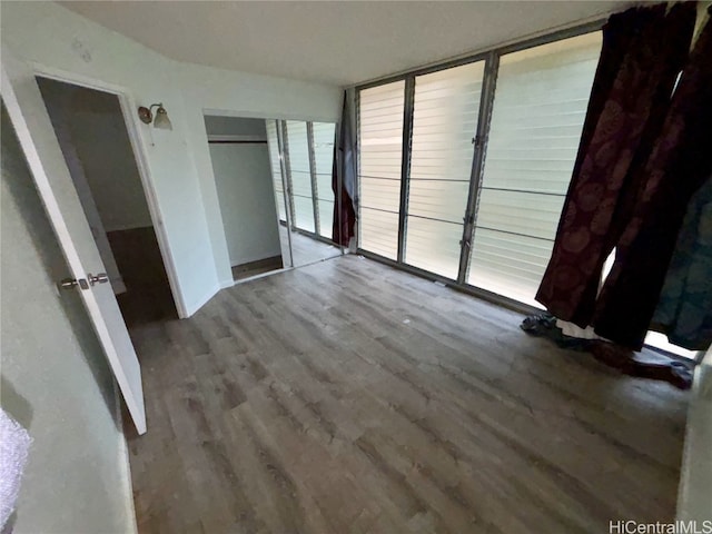 unfurnished bedroom with expansive windows, hardwood / wood-style floors, and a closet