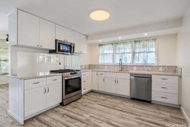 kitchen with stainless steel appliances, a wealth of natural light, a sink, and white cabinetry