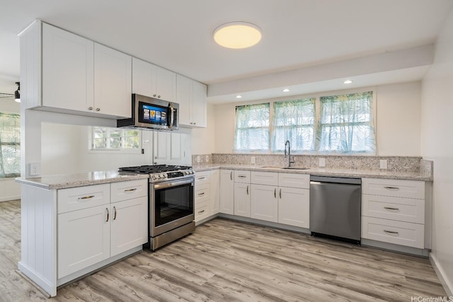 2340 University Ave, Honolulu, HI 96822 - kitchen featuring white cabinets, stainless steel appliances, a sink, light wood-style floors, and light stone countertops
