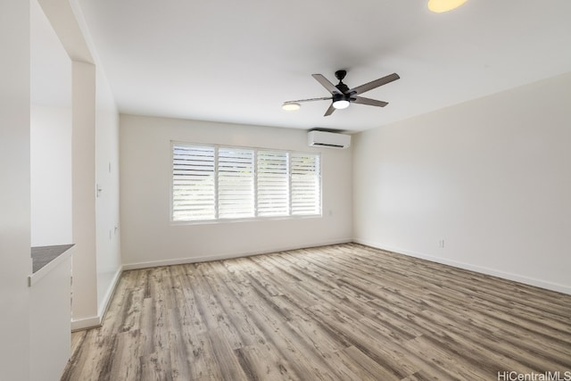 unfurnished room featuring ceiling fan, a wall mounted AC, wood finished floors, and baseboards