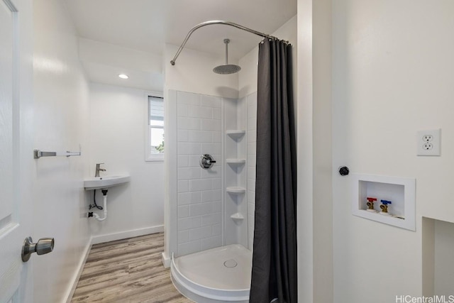 full bath featuring a stall shower, baseboards, and wood finished floors