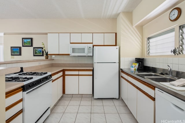 kitchen with white appliances, tasteful backsplash, white cabinetry, and sink