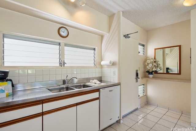 kitchen with white dishwasher, sink, white cabinets, and decorative backsplash