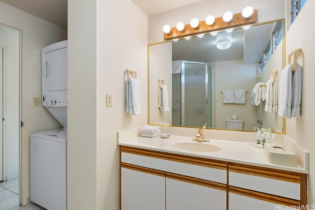 bathroom with tile patterned floors, stacked washer and dryer, toilet, a shower with shower door, and vanity