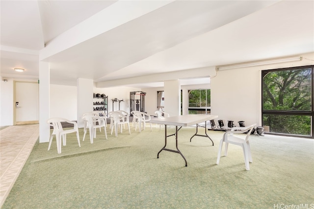 carpeted dining space featuring high vaulted ceiling