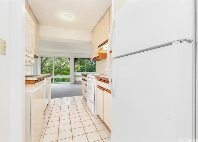 kitchen featuring white appliances, washer / clothes dryer, a textured ceiling, white cabinetry, and light tile patterned floors