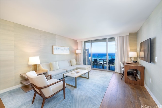 living room featuring a water view, hardwood / wood-style flooring, and a wall of windows