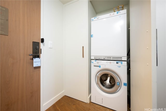 clothes washing area featuring hardwood / wood-style flooring and stacked washer and dryer