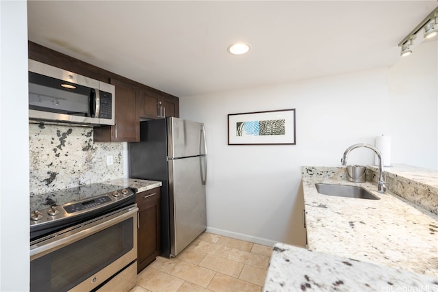 kitchen featuring light stone counters, sink, dark brown cabinets, and stainless steel appliances