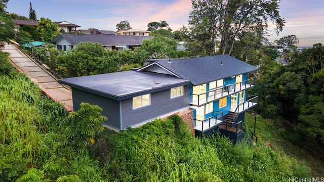 back house at dusk featuring a balcony