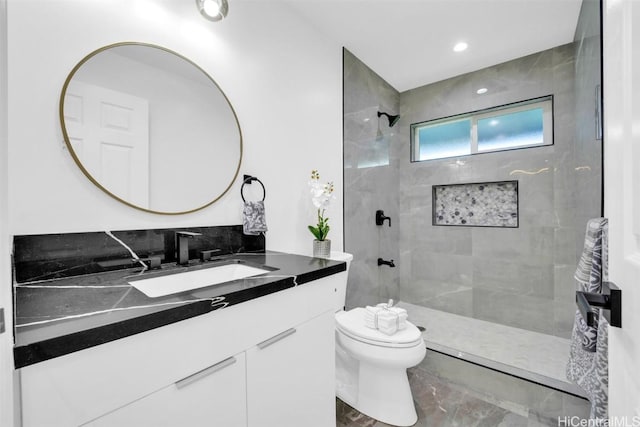 bathroom with vanity, tiled shower, and toilet