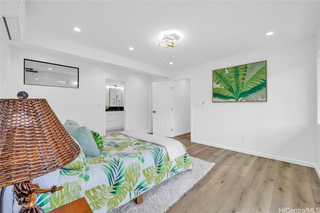 bedroom with connected bathroom and light hardwood / wood-style flooring