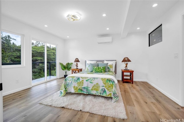 bedroom featuring beam ceiling, light hardwood / wood-style floors, access to outside, and an AC wall unit