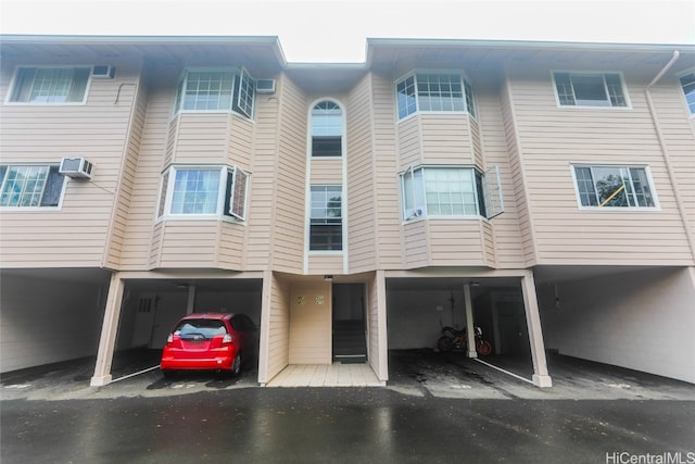 rear view of house with an AC wall unit and a carport