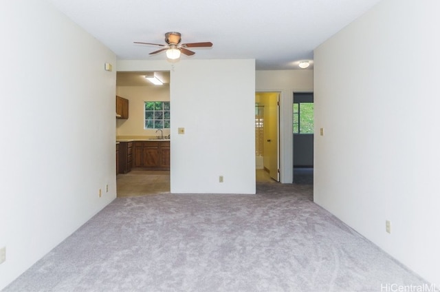 carpeted spare room featuring ceiling fan and sink