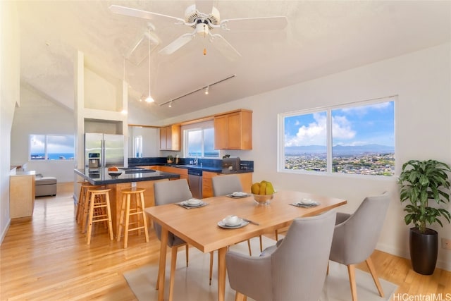 dining room with ceiling fan, sink, lofted ceiling, and light wood-type flooring