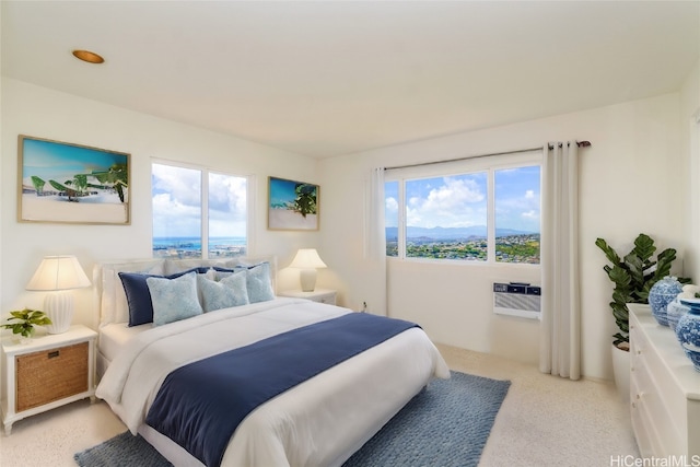 bedroom with light carpet, a wall unit AC, and multiple windows