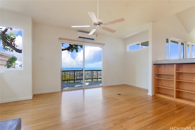 unfurnished room with ceiling fan, a wall unit AC, light wood-type flooring, and a wealth of natural light