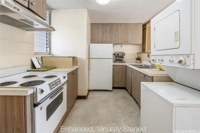 kitchen featuring a textured ceiling, white appliances, stacked washer / dryer, and sink