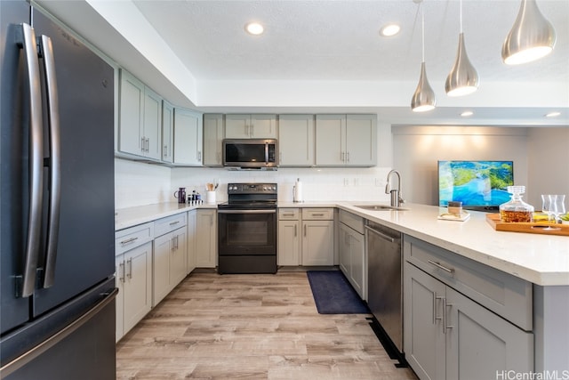 kitchen featuring gray cabinetry, stainless steel appliances, sink, pendant lighting, and light wood-type flooring