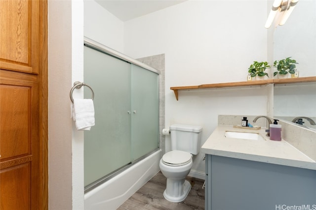 full bathroom featuring vanity, enclosed tub / shower combo, hardwood / wood-style flooring, and toilet