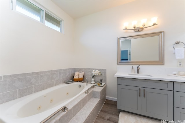 bathroom with vanity, hardwood / wood-style floors, and tiled bath