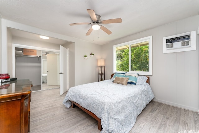 bedroom featuring a wall mounted air conditioner, a closet, light wood-type flooring, and ceiling fan