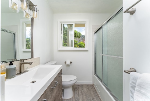 full bathroom with toilet, hardwood / wood-style floors, vanity, and shower / bath combination with glass door