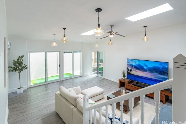 living room featuring ceiling fan, hardwood / wood-style flooring, and a skylight