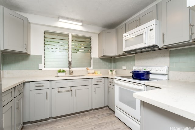 kitchen with gray cabinetry, sink, light wood-type flooring, and white appliances