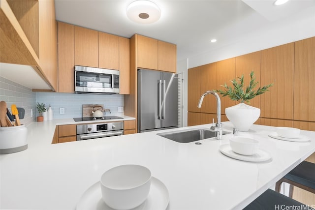 kitchen with a breakfast bar area, kitchen peninsula, stainless steel appliances, sink, and tasteful backsplash