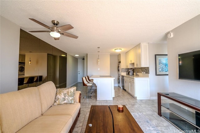 living room with ceiling fan, sink, washer / dryer, and a textured ceiling