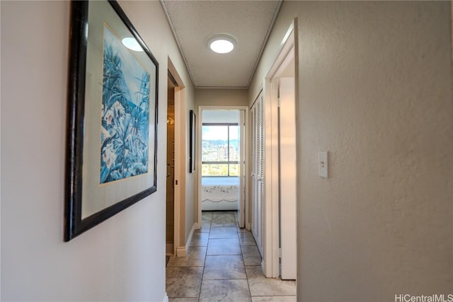 hall with a textured ceiling and light tile patterned floors