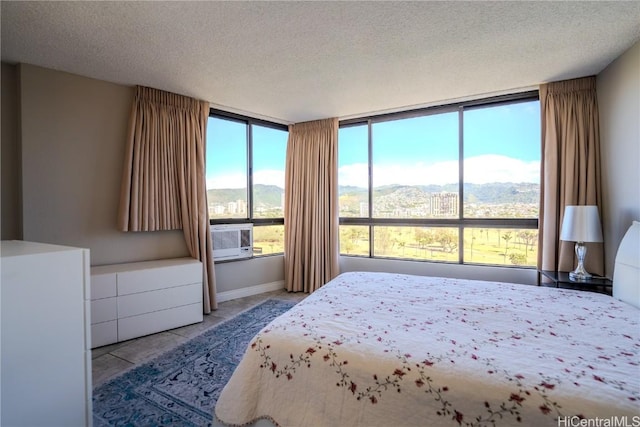 bedroom featuring cooling unit, light tile patterned flooring, a mountain view, and a textured ceiling