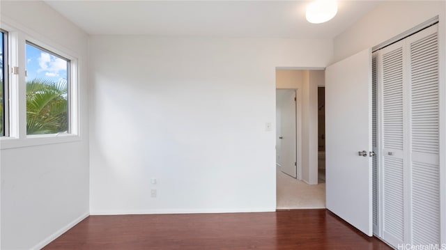 unfurnished bedroom with dark wood-type flooring and a closet