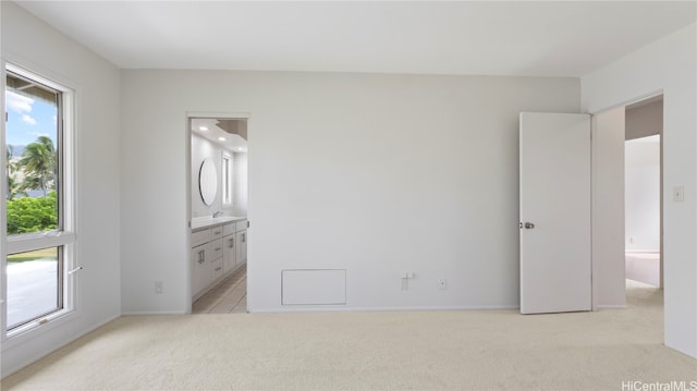 unfurnished bedroom featuring light colored carpet and ensuite bath