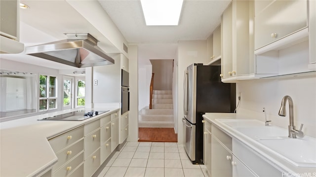 kitchen with sink, white cabinetry, a skylight, light tile patterned floors, and appliances with stainless steel finishes