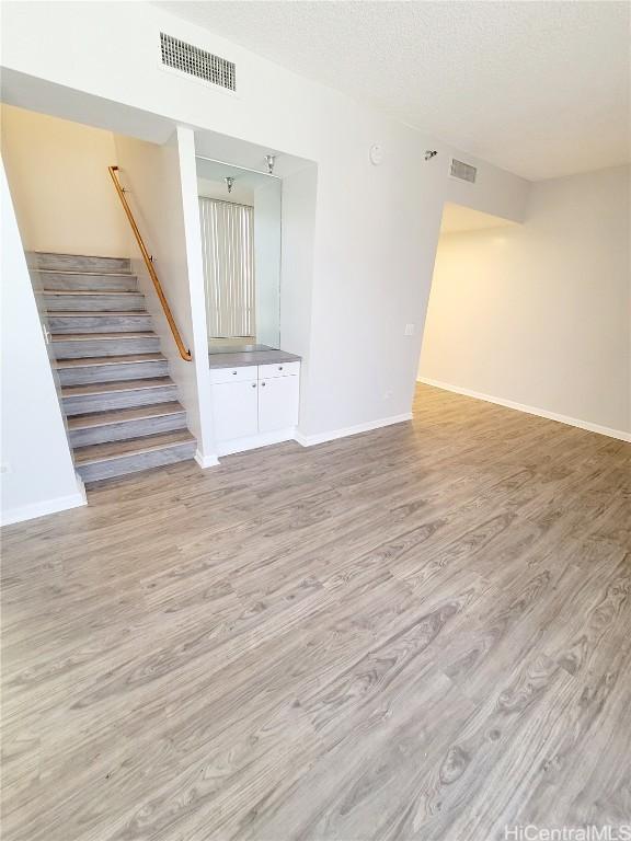 unfurnished living room featuring light hardwood / wood-style flooring and a textured ceiling