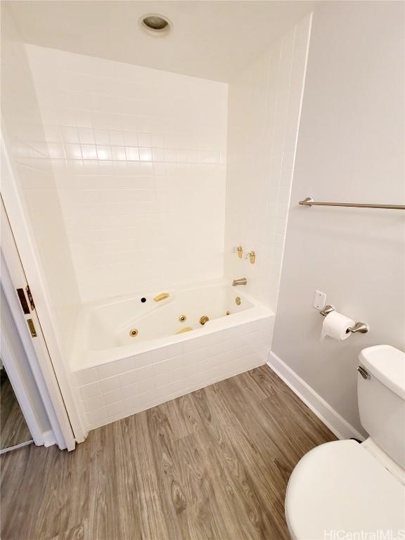 bathroom with shower / bathtub combination, toilet, and hardwood / wood-style floors